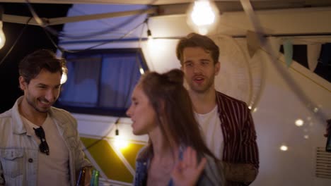 group of young friends spending time on the camping side, drinking beer and dancing.