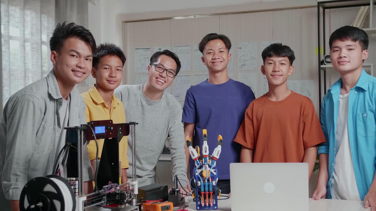 과 3d 프린팅을 가진 아시아 남자와 소년들은 학교에서 사이보그 손에 대해 논의하는 동안 카메라에 미소 짓고 있습니다.