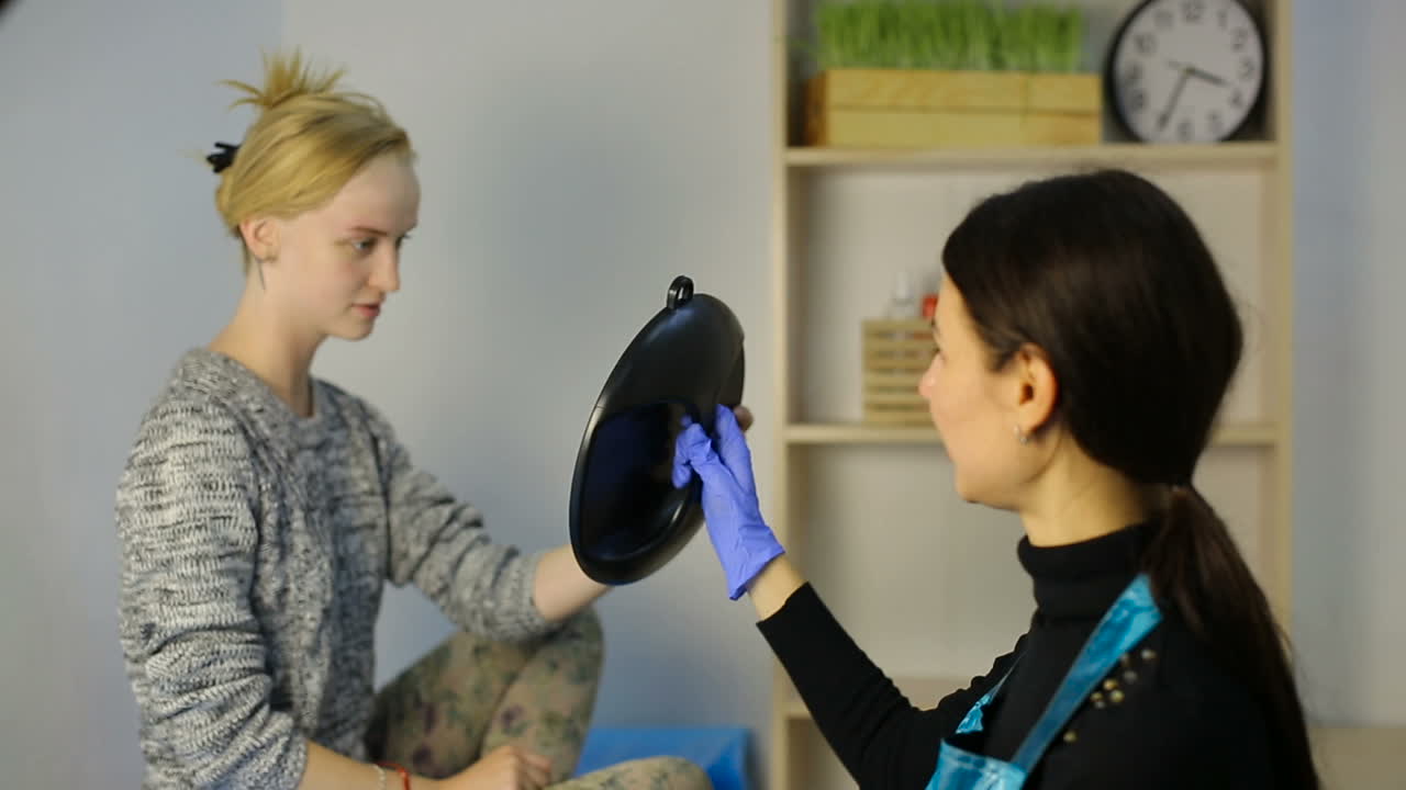 Woman after make up. Woman looks at herself in the mirror after eyebrow make up