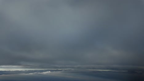 a pilot’s view taken from a jet ccokpit while flying during climb through layers of ethereal clouds at dawn at supersonic speed