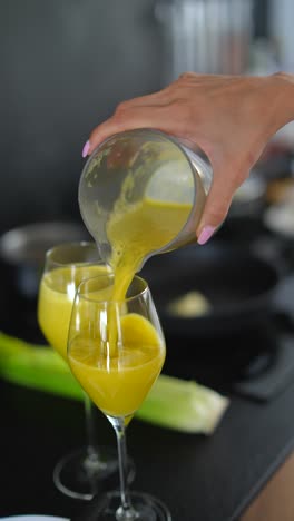 woman pouring healthy juice into glasses