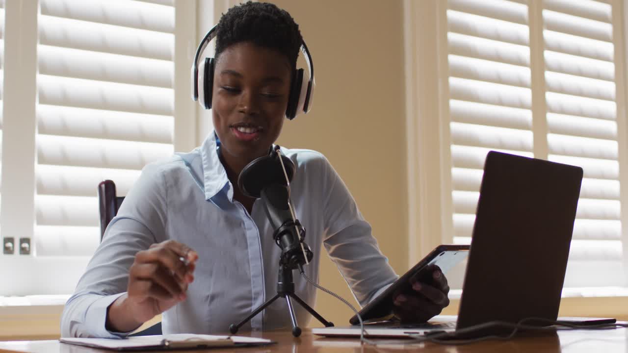 mujer afroamericana con auriculares tomando notas y cantando en casa