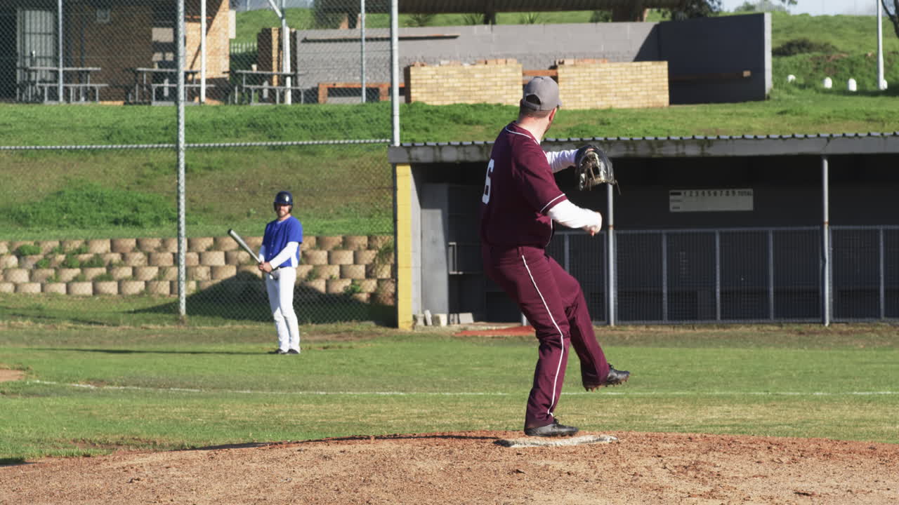 Due squadre di giocatori di baseball uomini che giocano a baseball, lanciano la palla su un campo da gioco, al rallentatore.
