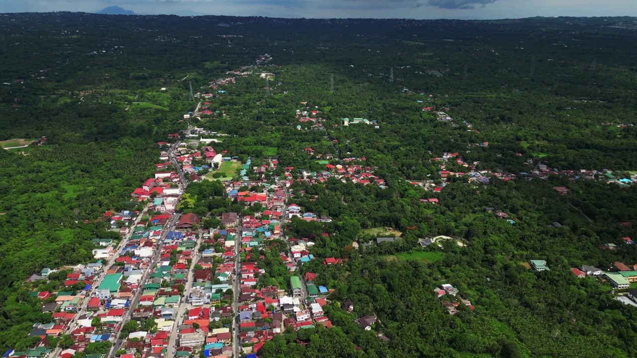 Bred etablerende luftoptagelse af boligområdet langs Rizal Mabini Burgos Road i Alfonso Cavite, Filippinerne, der viser provinsielle huse, grønne områder langs vejen og et fredeligt kvarter om dagen.