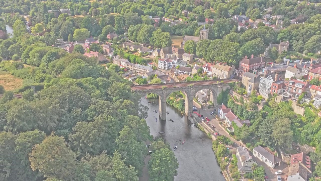 El viaducto ferroviario de Knaresborough cruza el río Nidd junto al histórico pueblo, rodeado de bosques y edificios de piedra en Knaresborough, North Yorkshire, Inglaterra, Reino Unido, retroceso de dron