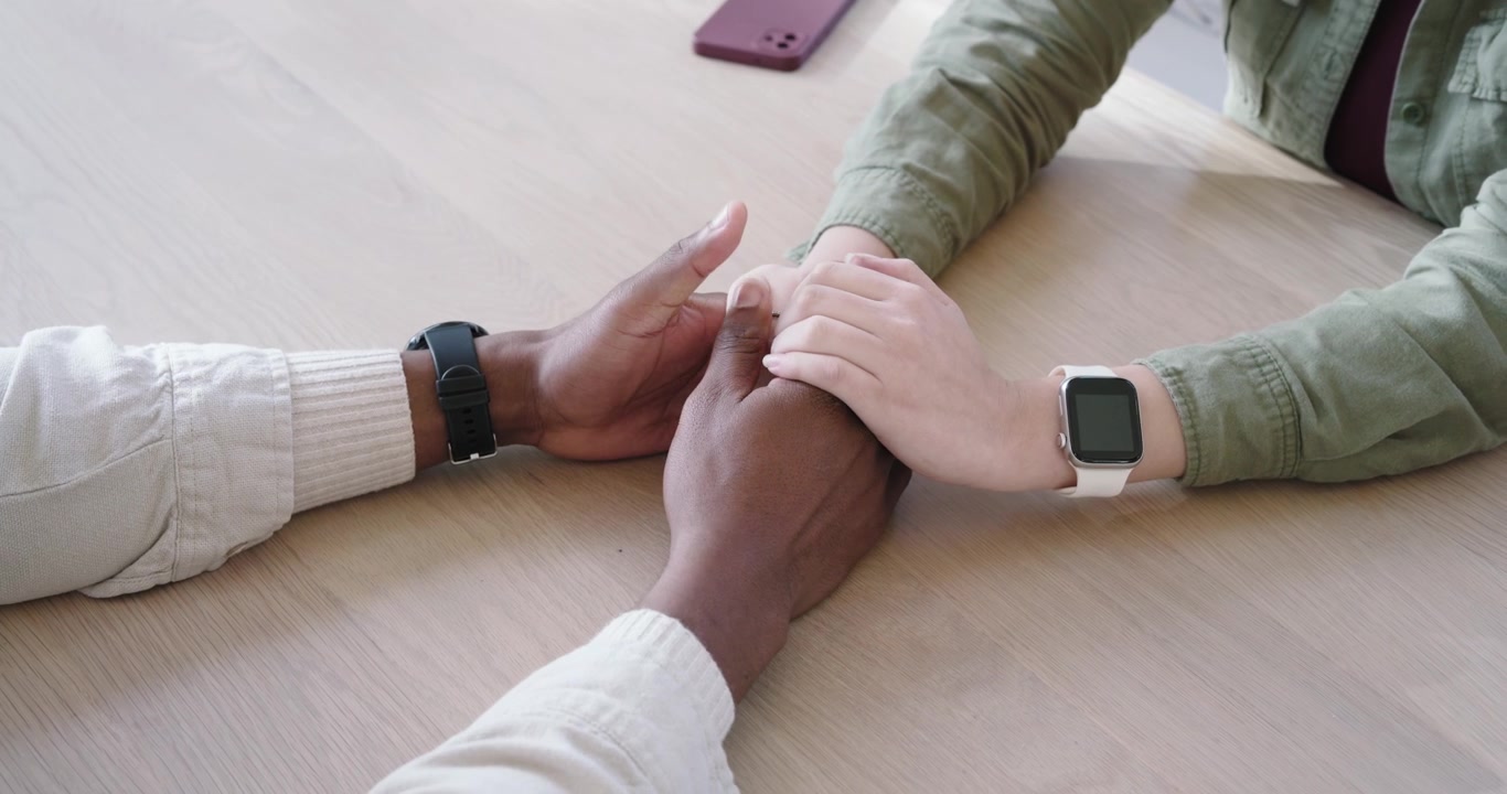 La mano sinistra cambia presa dopo il riposo, strofinando le dita del partner sul tavolo vicino a una tazza per conforto
