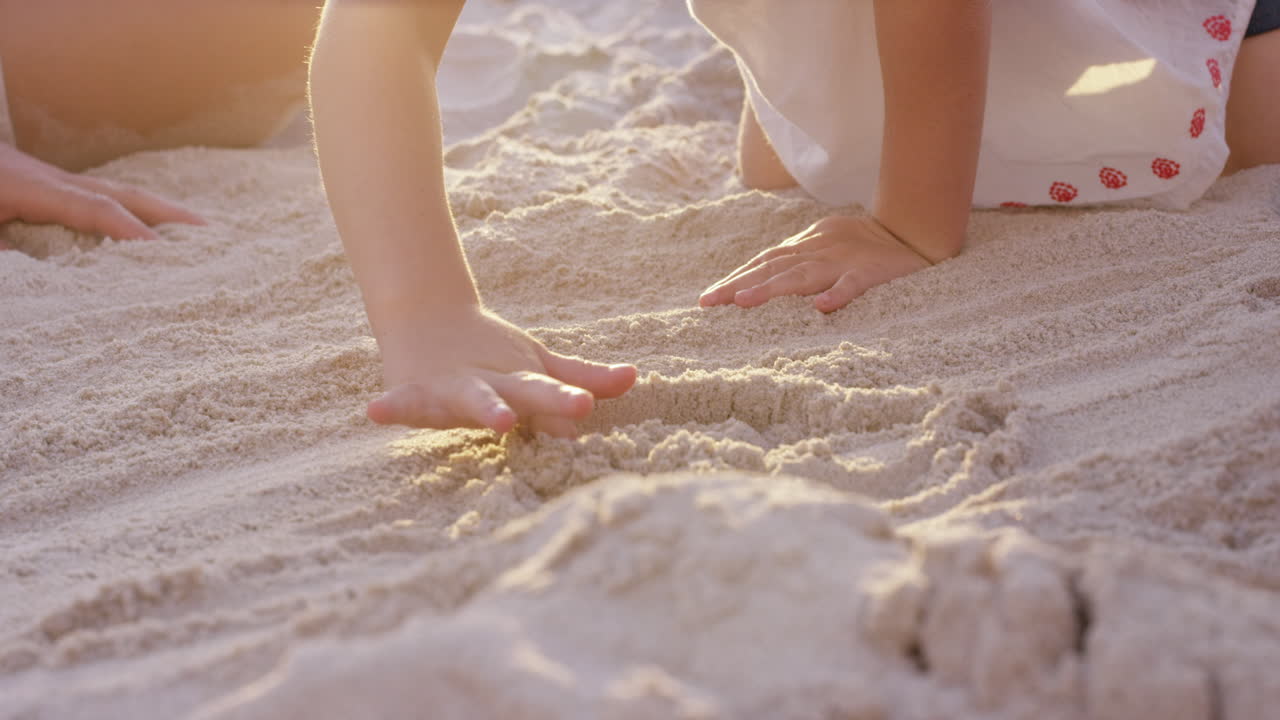 해가 지면 모래에 그림을 그리는 해변에서 행복한 가족이 놀고 있습니다.