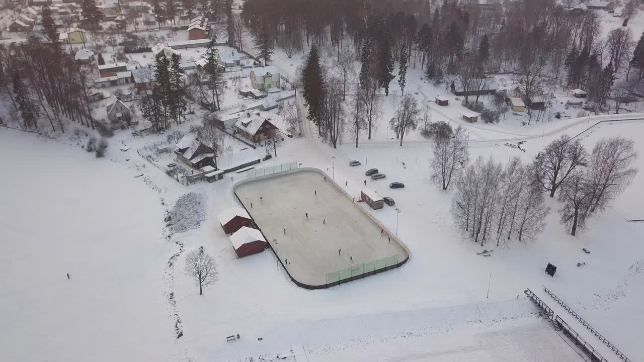 campo de hockey al aire libre en un pequeño parque de aldea, terreno cubierto de nieve, inclinación aérea hacia abajo