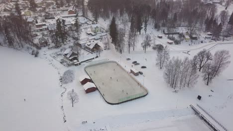 outdoor hockey field in small village park, snow cover ground, aerial tilt down