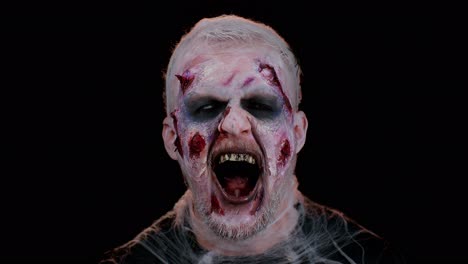 sinister man halloween crazy zombie with bloody wounded scars face trying to scare on black room