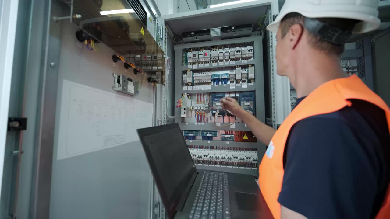 el ingeniero eléctrico que trabaja comprueba la tensión de corriente eléctrica y la sobrecarga en la parte delantera del gabinete del centro de carga o de la unidad de consumo para el mantenimiento en la sala principal del sistema de distribución de energía.