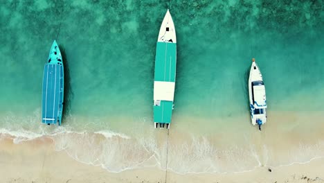 aerial top down view of three long boats parked on the seashore