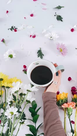 woman holding coffee cup surrounded by flowers
