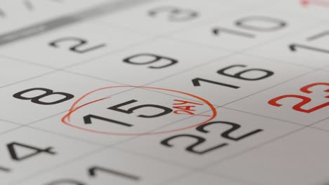 de cerca: marcando un día de pago en un calendario de papel con una pluma roja