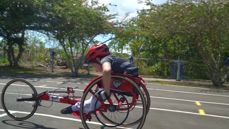 un niño con discapacidad conduciendo un handbike en una carrera de paraciclismo