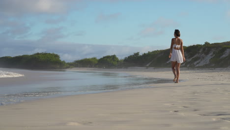 bella viajera corriendo hacia la playa de bahía tortuga con olas rompiendo lentamente en las galápagos