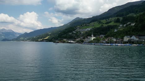 Long-shot-of-Alpine-mountain-landscape-with-town-setup-near-lake-shore