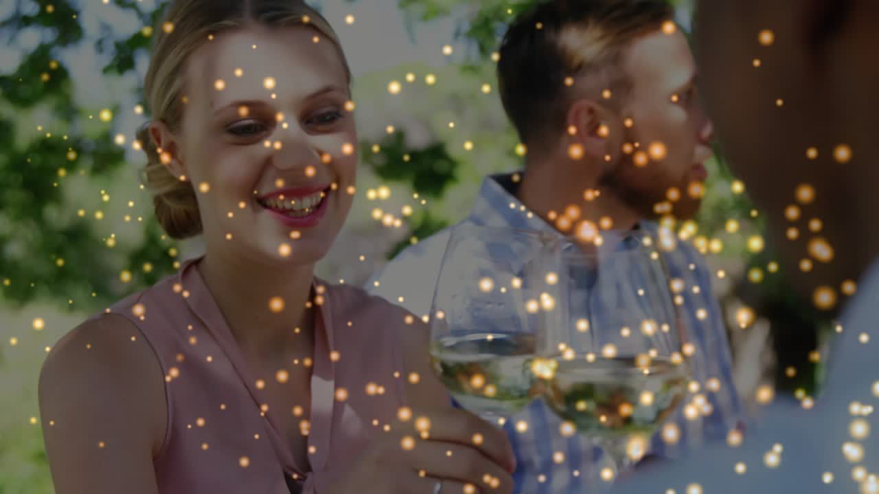 Woman raising wine glass, sniffing, sipping after offscreen cue in catering, golden bokeh floating