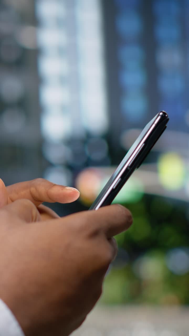 Video verticale Un uomo adulto di colore cammina e scorre le app sul suo cellulare