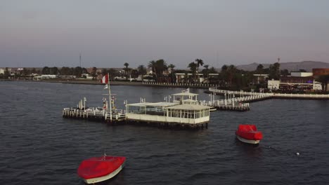 Paracas-bay-pier-with-peruvian-flag-Ica,-Peru---Drone-UHD