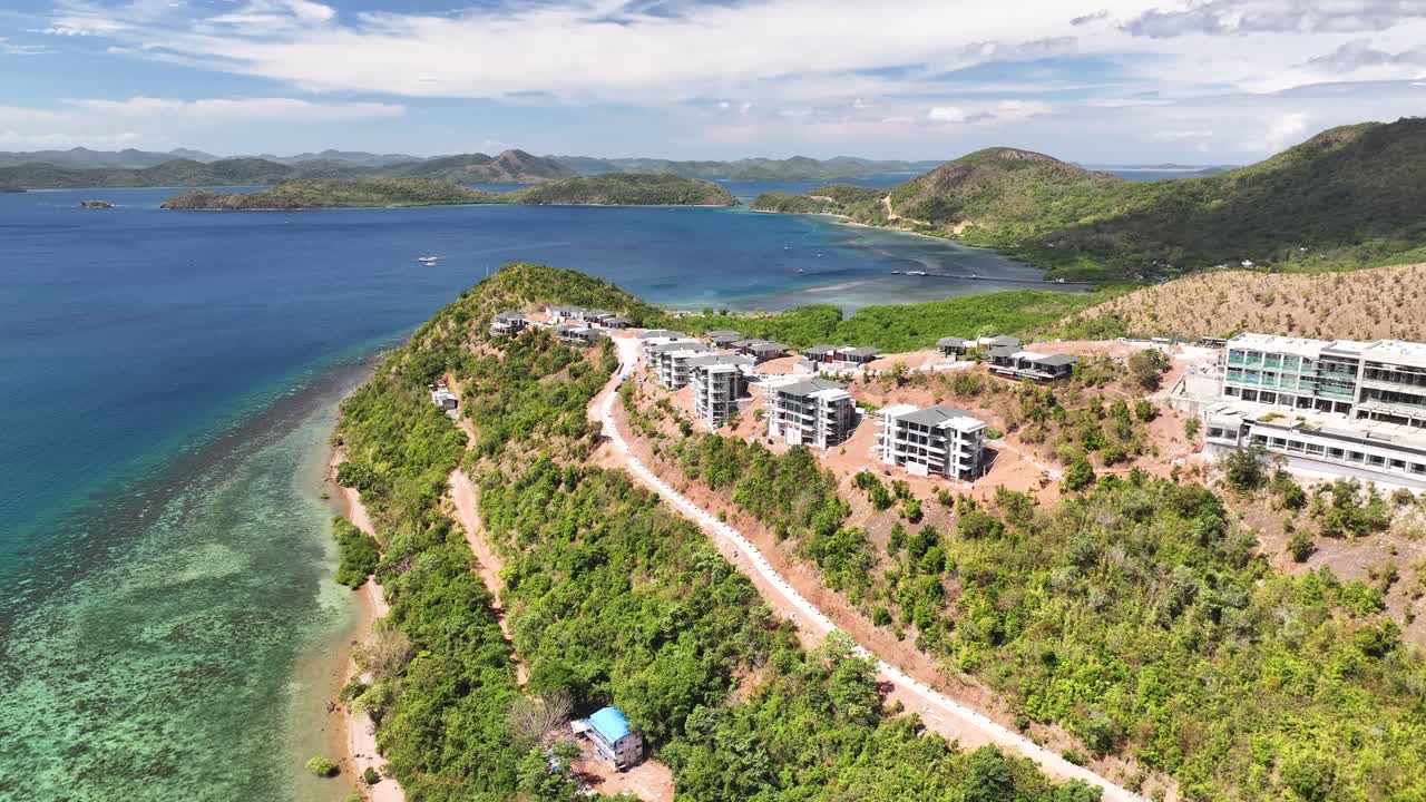 Construction Of Modern Resort Buildings On Lush Green Hill Overlooking Blue Sea In Busuanga, Palawan, Philippines. aerial orbiting shot