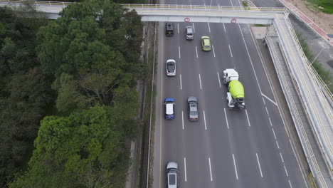 Overhead-Drohnenclip,-Der-Einer-Schlange-Von-Autos-Und-Lastwagen-Folgt,-Die-Sich-Auf-Einer-Schnelllebigen,-Von-Bäumen-Gesäumten-Autobahn-Mit-Mehreren-Fahrspuren-Bewegen