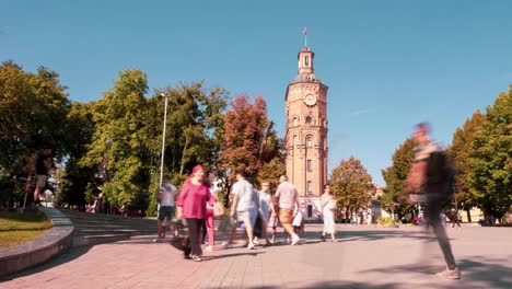 timelapse video of people walking in a beautiful park with many trees and a clock tower