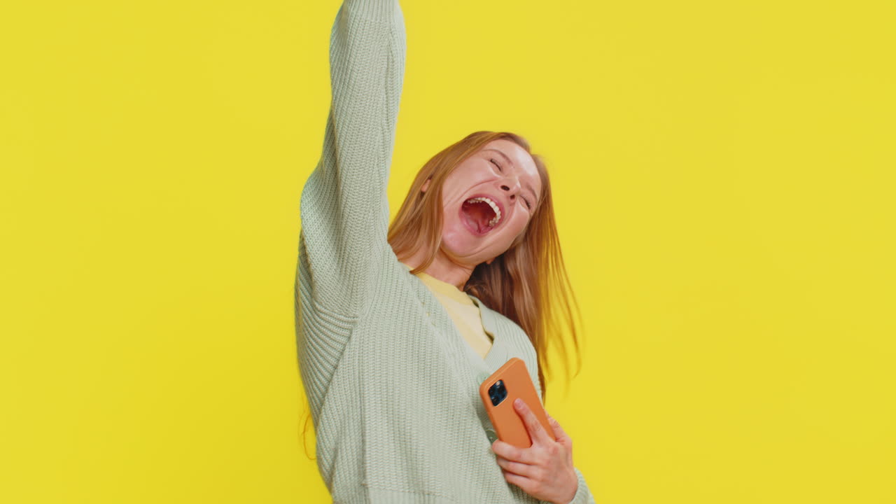 Happy woman playing racing drive simulator shooter video games on smartphone celebrate victory win