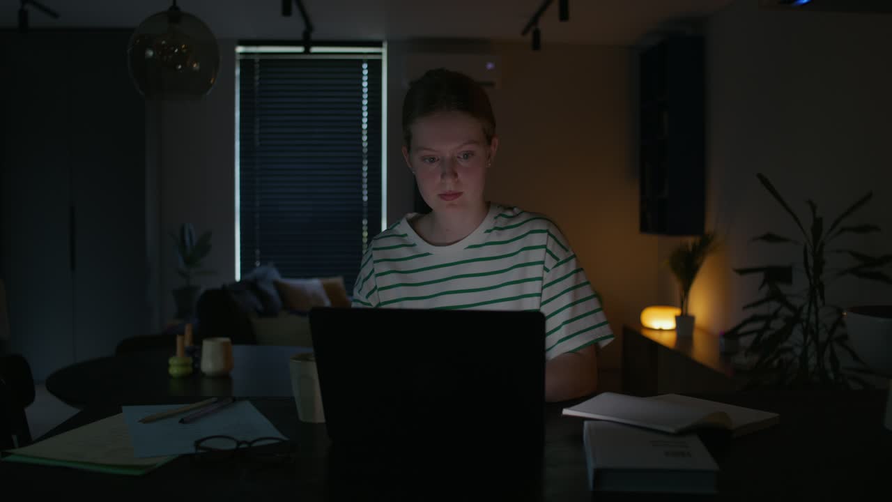 una adolescente estudiando hasta tarde en la noche.
