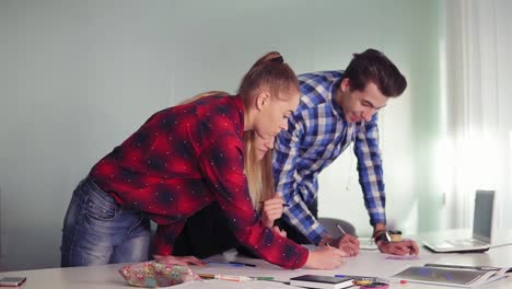 reunión del equipo de diseñadores de interiores en la oficina creativa. jóvenes hipsters haciendo bocetos de pie en la mesa y discutiendo