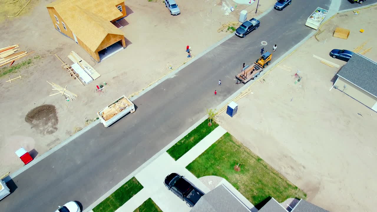 Flying over rooftops of new houses and people walking through New Subdivision