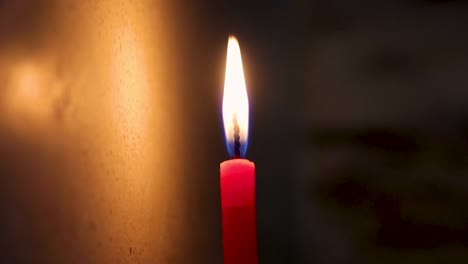 lighted candle flickering in dark environment from flat angle