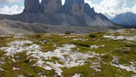 Antenne-Fliegt-über-Felsige-Landschaft-Mit-Blick-Auf-Tre-Cime-Di-Lavaredo-Mit-Wolken-über-Den-Gipfeln-In-Der-Ferne