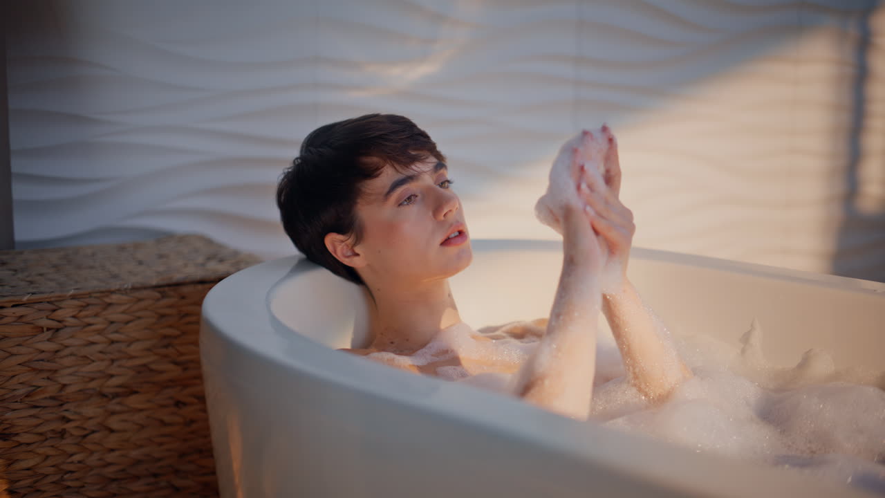 Sexy girl soaking bubble bath washing hands enjoying self care morning closeup