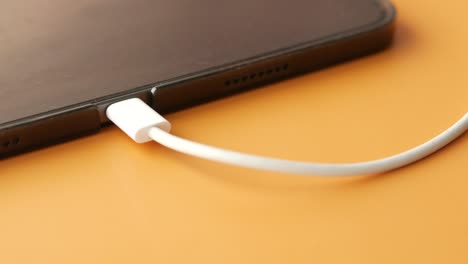 charging digital tablet with a cable on color background .