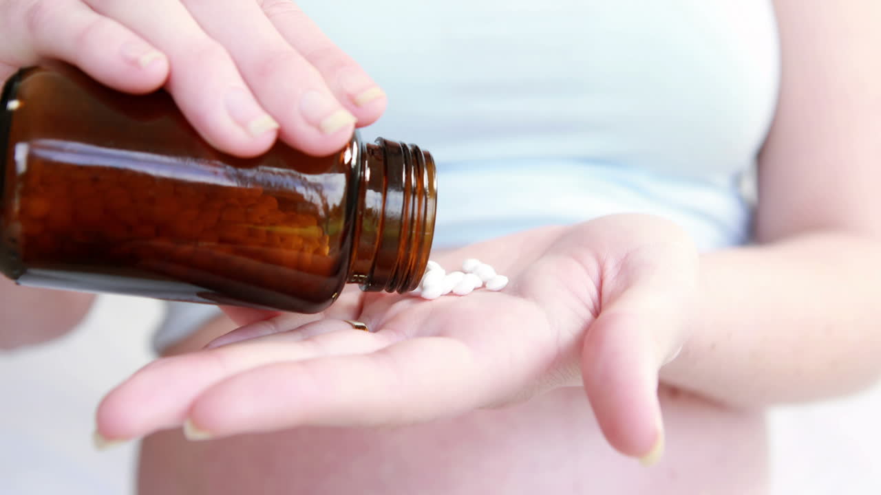 Donna incinta che prende pillole da un barattolo