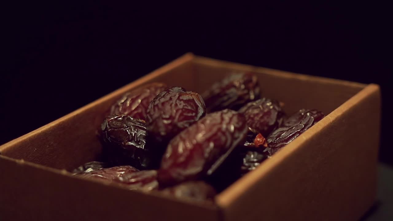 hand pick fresh Medjool dates from rotating cardboard box, close up
