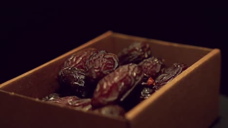 hand pick fresh medjool dates from rotating cardboard box, close up