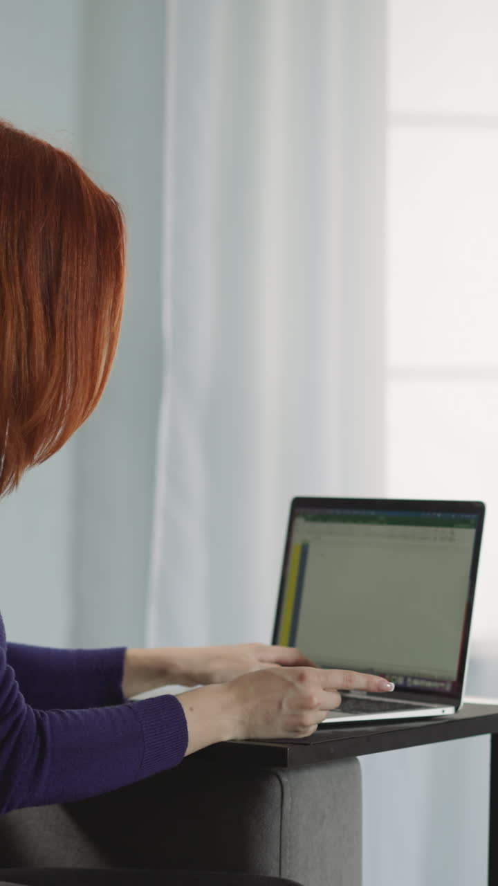 una mujer pelirroja compra servicios en línea escribiendo los detalles de la tarjeta de crédito bancaria en el sitio web. la cliente utiliza una computadora portátil moderna para hacer pagos rápidos desde casa