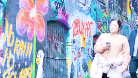 people walking past colorful graffiti in hosier lane