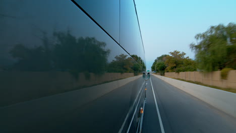 side view of a public bus, shuttle, or school bus driving and the road reflection on it