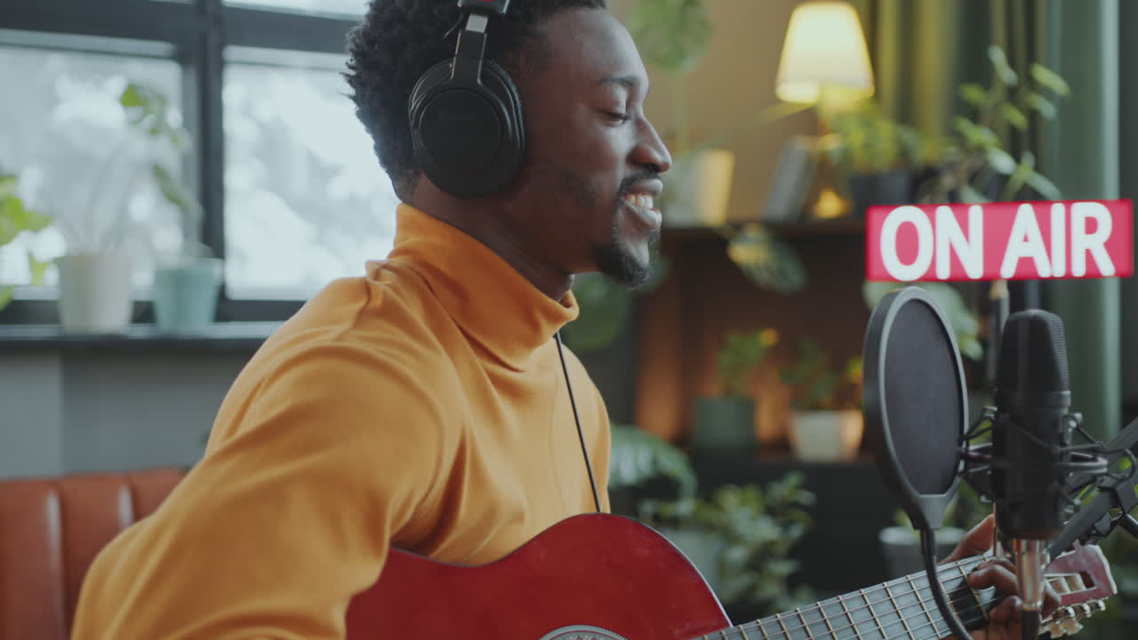 Musicista Canta e Suona la Chitarra durante Programma Radiofonico in Studio di Trasmissione
