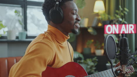 musician singing and playing guitar during radio show in broadcasting studio