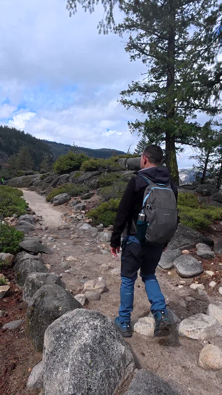 Hombre haciendo senderismo en un sendero de montaña rocoso con una mochila