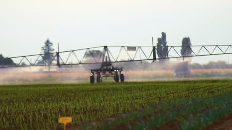 pulverizador de plaguicidas de brazo ancho agrícola, que se mueve automáticamente lentamente a través de un campo de ensayos de cultivos múltiples en un día de viento, enfoque selectivo