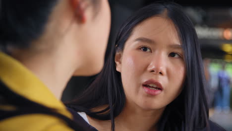 close up of two young female friends outside meeting and talking in urban setting