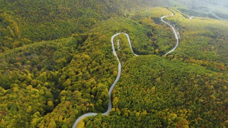 aerial footage of twisty mountain road in autumn forest - 12