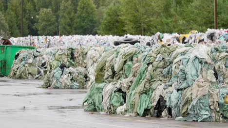 stacks of compact plastic garbage stored for recycling in landfill near forest