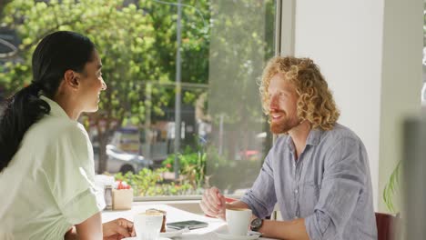 happy diverse couple drinking coffee and talking at a table in cafe