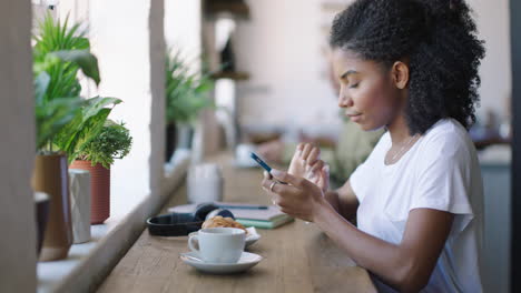 mujer negra, estudiante y teléfono escribiendo en una cafetería